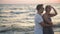 Portrait of Hansome Boyfriend Hugging His Blonde Girlfriend Standing Near the Sea During Sunset.