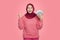 Portrait of the happiest Asian Muslim woman holding rupiah money isolated over pink background.