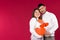 Portrait of happiest couple with red hearts over red background with empty blank space. St.Valentine`s Day