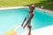 Portrait of happy african american girl with inflatable ring standing at poolside on sunny day