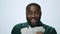 Portrait of happy african american man counting money on grey background.