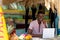 Portrait of happy african american man using laptop behind counter of surf hire beach shack
