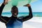 Portrait of happy african american senior man carrying surfboard on head at beach