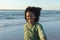 Portrait of happy african american woman looking at camera and smiling on beach at sundown