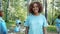 Portrait of happy Afro-American girl in volunteer uniform in polluted forest