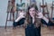 Portrait of happy artist in the art studio shows her hands stained with paints