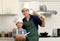 Portrait of happy Asian father and son kid with apron chef hat hold wooden rolling kneading stick and bread flour bowl at kitchen