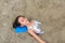 Portrait of happy asian little child girl buried in the sand at the beach. Close up kid playing with sand