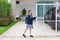 Portrait of happy asian little kid girl in school uniform trying push and pull door fence of house to close or open before leave