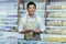 portrait of happy asian male small business owner standing in grocery store behind counter. Male manager with a tablet