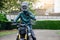 Portrait of happy asian man in green leather jacket riding on motorbike in city street and showing thumb up