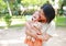 Portrait of happy Asian mother cuddle daughter and hugging teddy bear doll in the garden. Mom and child girl with love and