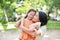 Portrait of happy Asian mother cuddle daughter and hugging teddy bear doll in the garden. Mom and child girl with love and