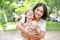 Portrait of happy Asian mother cuddle daughter and hugging teddy bear doll in the garden. Mom and child girl with love and