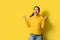 Portrait of a happy Asian woman screaming an excited and celebrating success isolated over yellow background. Succeed