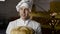 Portrait of happy baker in uniform sniffs a fresh loaf of bread and smiles