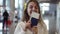 Portrait of happy, beautiful American woman showing passport with flight tickets and waving it. Looking and smilling to