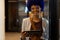 Portrait of happy biracial casual businesswoman with blue afro using tablet in office corridor