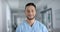 Portrait of happy biracial male doctor wearing scrubs, smiling, slow motion