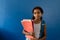 Portrait of happy biracial schoolgirl holding notebooks on blue background with copy space
