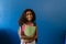 Portrait of happy biracial schoolgirl with school bag holding notebooks on blue background