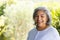 Portrait of happy biracial senior woman laughing in sunny garden, copy space