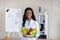 Portrait of happy black dietitian in lab coat holding bowl of fresh fruits and vegetables, smiling at camera at clinic