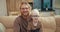 Portrait of a happy blond man in glasses and his little albino son in blue glasses who are sitting on a cream sofa in a