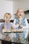 Portrait of happy boy with sister tasting spatula mix with cookie batter in kitchen