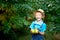 Portrait of a happy boy six years old in blue clothes and hat in a garden with Apple trees and holding apples