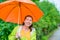 Portrait of happy brunette wearing a raincoat under an orange