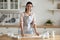 Portrait of happy brunette woman in apron, rolling out dough.