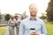 Portrait of happy businessman holding disposable cup with colleagues standing in background