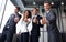 Portrait of happy businesspeople standing in office showing thumb up.