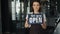 Portrait of happy businesswoman in apron holding open sign standing in new cafe