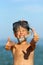 Portrait of happy caucasian boy at the seaside wearing a diving mask and showing like gesture