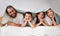 Portrait of happy caucasian family of four lying together on bed with a sherpa blanket over their heads. Carefree