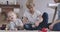 Portrait of happy Caucasian family resting indoors. Mother giving toy to her baby daughter. Schoolboy playing with mom