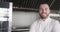 Portrait of happy caucasian male chef with beard smiling in kitchen, copy space, slow motion