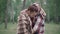 Portrait of happy Caucasian man kissing woman on cheek. Positive adult couple standing in park or forest covered with