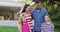 Portrait of happy caucasian parents, son and daughter standing in garden together smiling