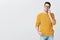Portrait of happy charismatic young handsome man in glasses and yellow trendy sweater holding hand in pocket relaxed and