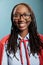 Portrait of happy cheerful smiling heartily young superhero woman wearing mighty hero red cape on blue background.