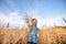 Portrait happy child in a field of autumn wheat pulls his hands to the top and holds a bouquet of spikelets of crops