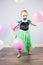 Portrait of happy child, playful with pink and white balloons and a princess dress