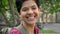 Portrait of happy college student with short black hair smiling at camera, standing on street near university, cheerful