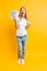 Portrait of happy contented girl with a bunch of banknotes and celebrating victory and success over yellow background