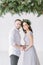 Portrait of happy couple isolated on white background. Bridesmaid in pine wreath and gray blue dress and groomsman