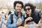Portrait of happy cute dark-skinned couple with afro hairstyle, strolling on food festival, tasting and drinking