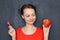 Portrait of happy cute woman holding apple and lollipop in hands